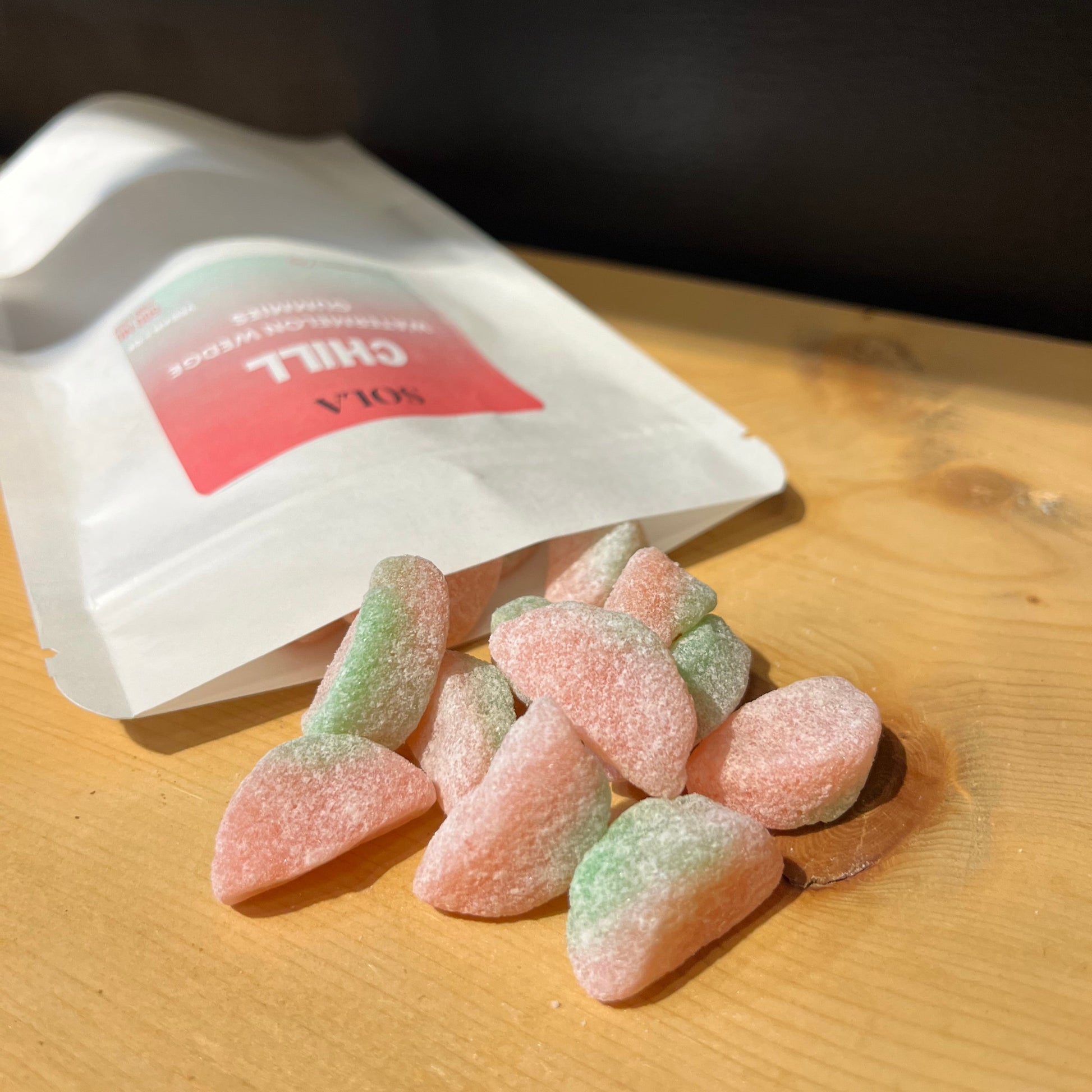 Several Chill Watermelon Wedges laying on a table — THC-free hemp-based CBD + CBG gummies — 25 mg each (500 mg total). Non-drowsy calm and pain relief. Gluten free (GF) and vegan.