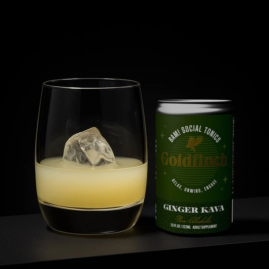 A third-full glass of Goldfinch Ginger Kava — a non-alcoholic adult beverage to relax and unwind, by BAM! Social Tonics, sits on a table next to the can from which it was poured.