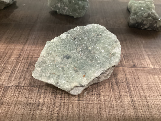 Assorted loose sea green epidote crystals on stones.