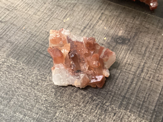 Assorted loose fire quartz crystals with orange/pink hues.