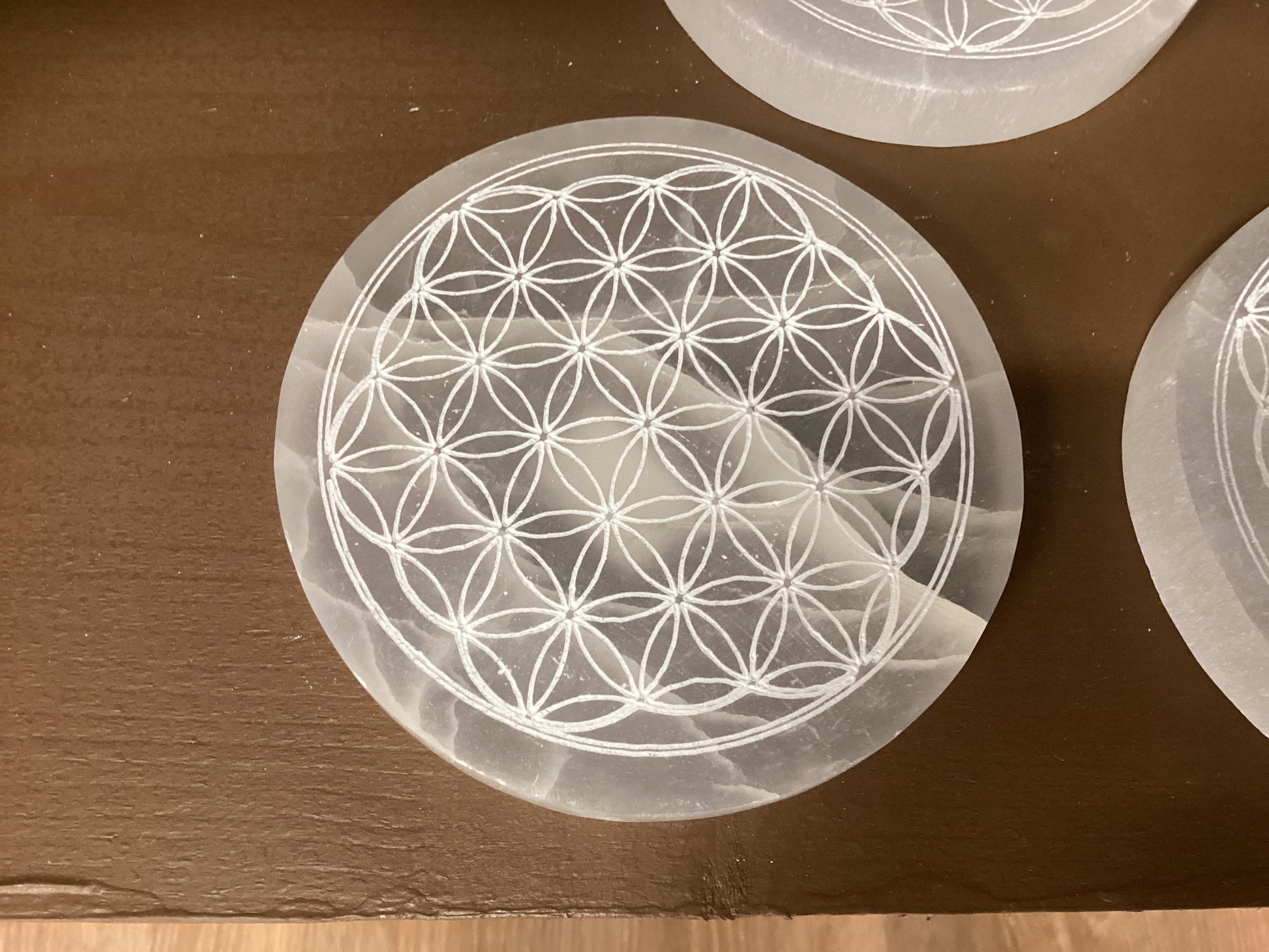 Semi-transparent white circular Selenite coaster with geometric design.